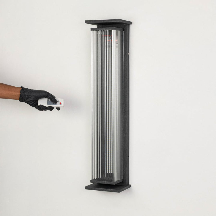 Minimal vertical wall light with black frame and ribbed glass diffuser displayed off on white background.