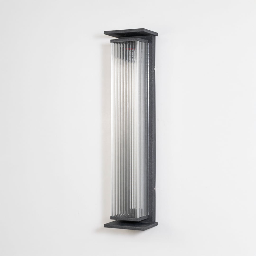Black ribbed wall light with vertical glass shade displayed off on plain white background surface.