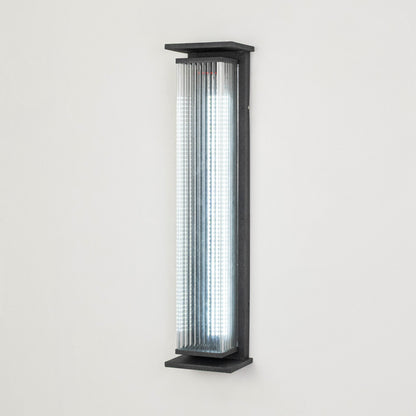 Black metal outdoor wall light on white background with ribbed glass shade for modern exterior decor.