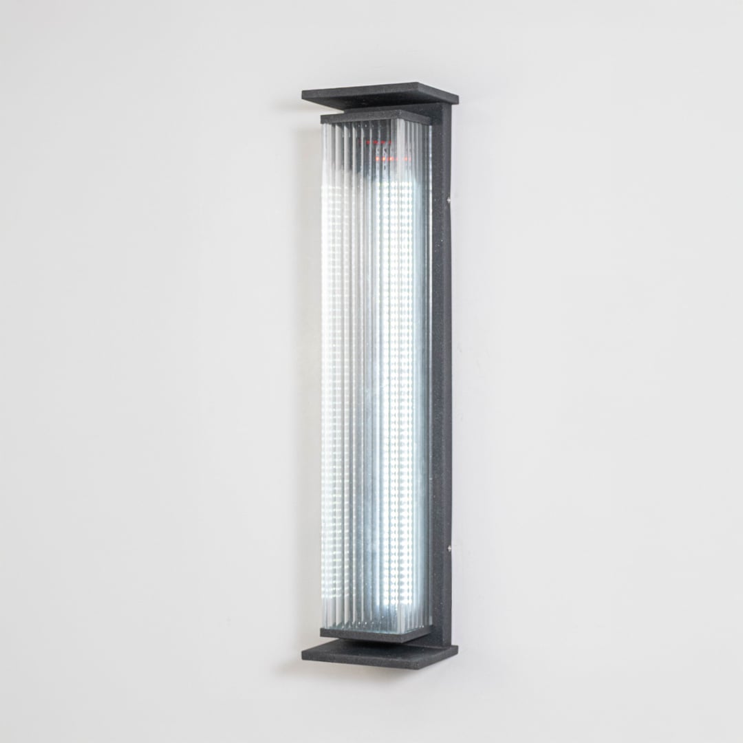Modern outdoor wall light in black metal with ribbed diffuser displayed on white background showcasing sleek contemporary exterior lighting.