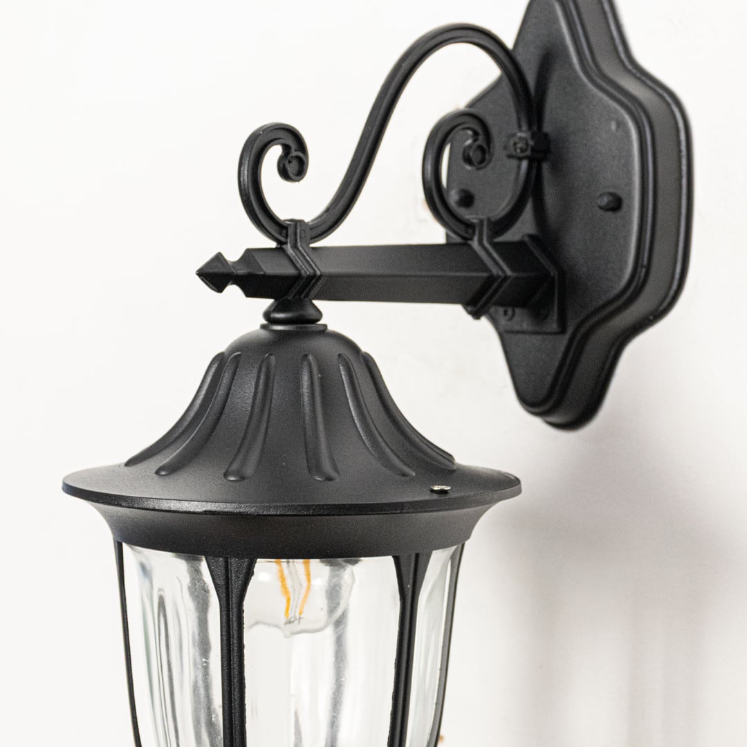 Closeup view of black metal outdoor lantern wall light highlighting clear glass panels sturdy frame and classic exterior lighting design.