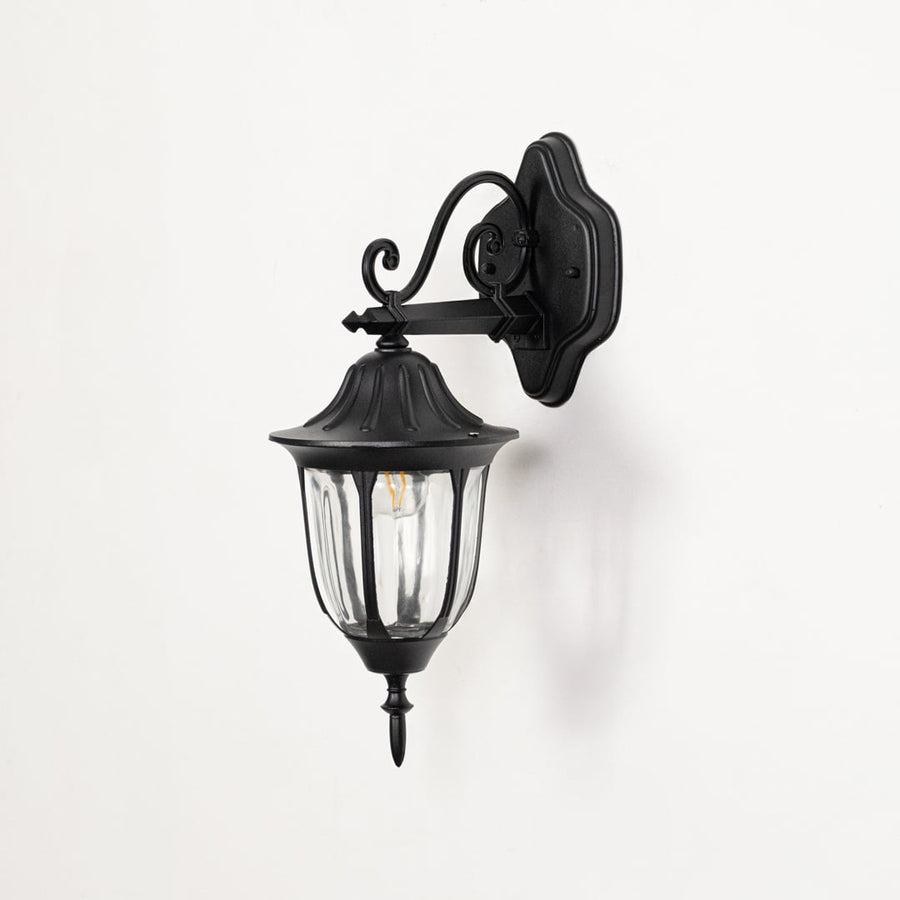 Black outdoor wall sconce turned off on white background showcasing downward lantern with curved glass vintage design.