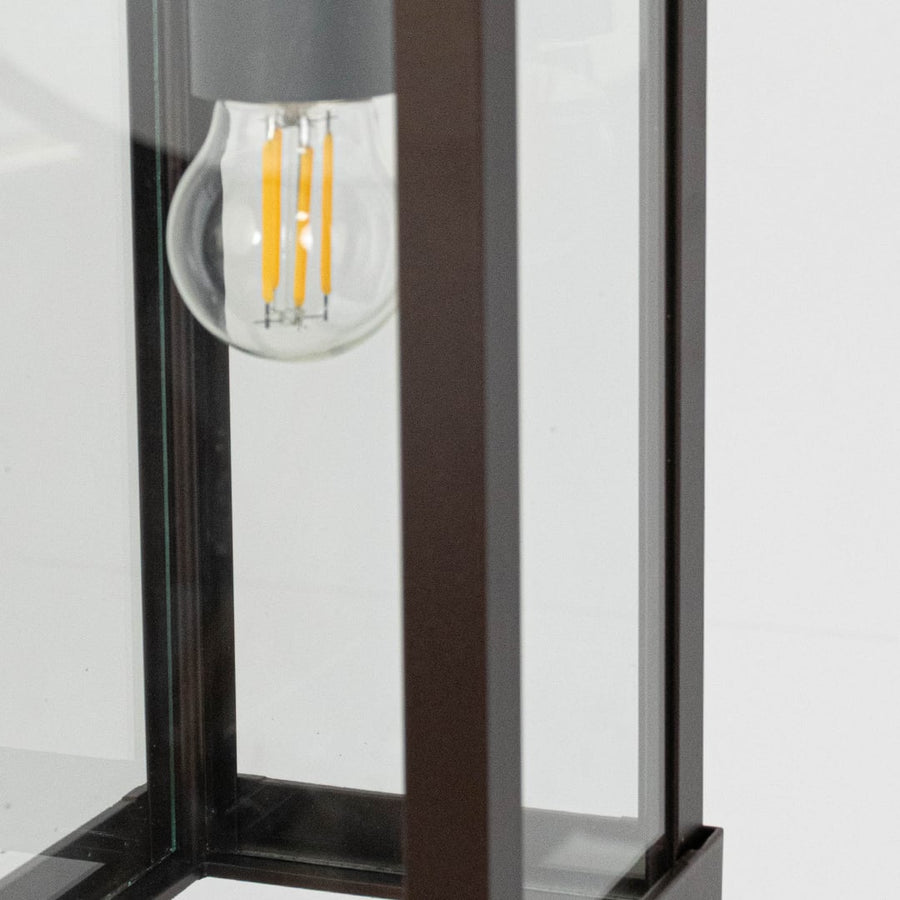 Closeup view of rectangular hanging lantern light showing bulb and sleek brown frame details.