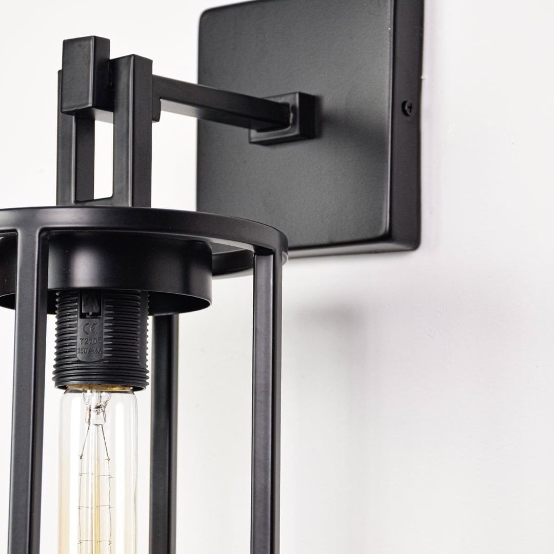 Closeup image of black metal outdoor wall light with clear glass shade for modern exterior wall decor.