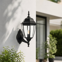 Decorative black metal outdoor wall lantern with curved arm for porch entrance driveway and exterior walls with warm lighting.
