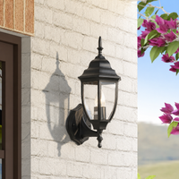 Classic black iron pointed top teardrop glass wall lantern sconce on white brick exterior facade for house patio lighting.