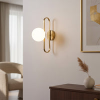 Modern gold metal wall light with white glass globe for elegant bedroom and luxury decor styling spaces.


