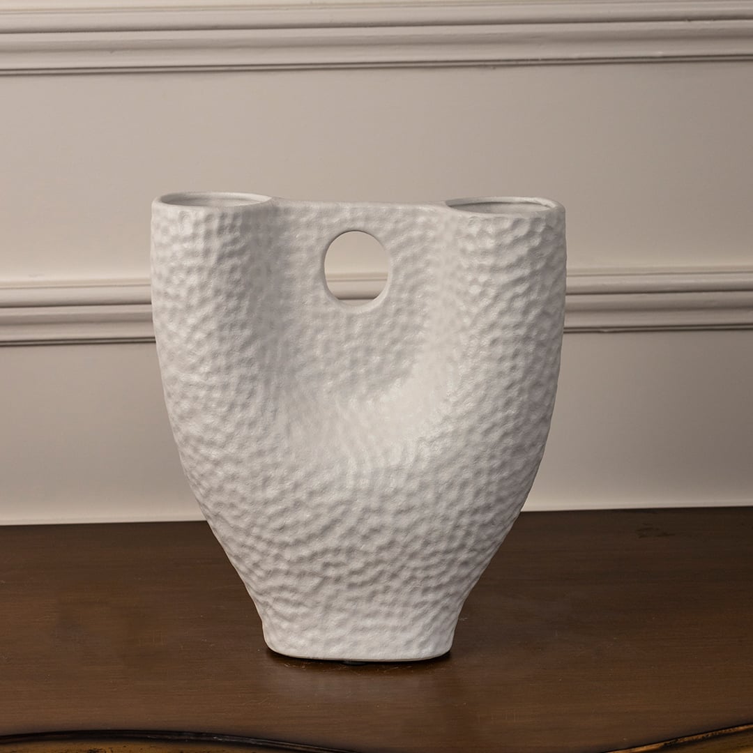 Matte white ceramic vase with hammered texture and dual openings displayed on white background showcasing modern artistry.