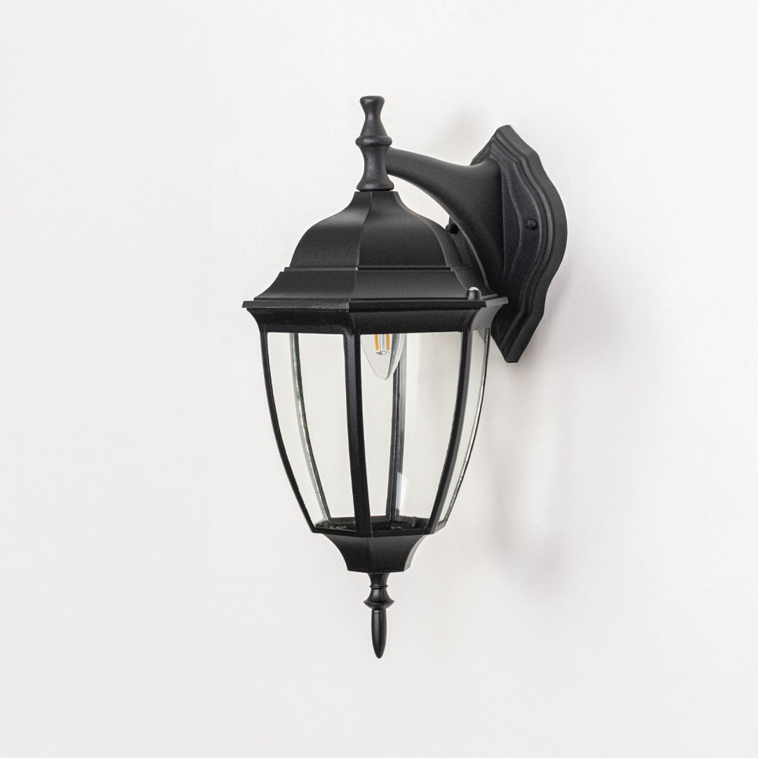 Outdoor wall lantern on white background highlighting black metal frame clear glass panels mounting plate and classic lantern form for product clarity.