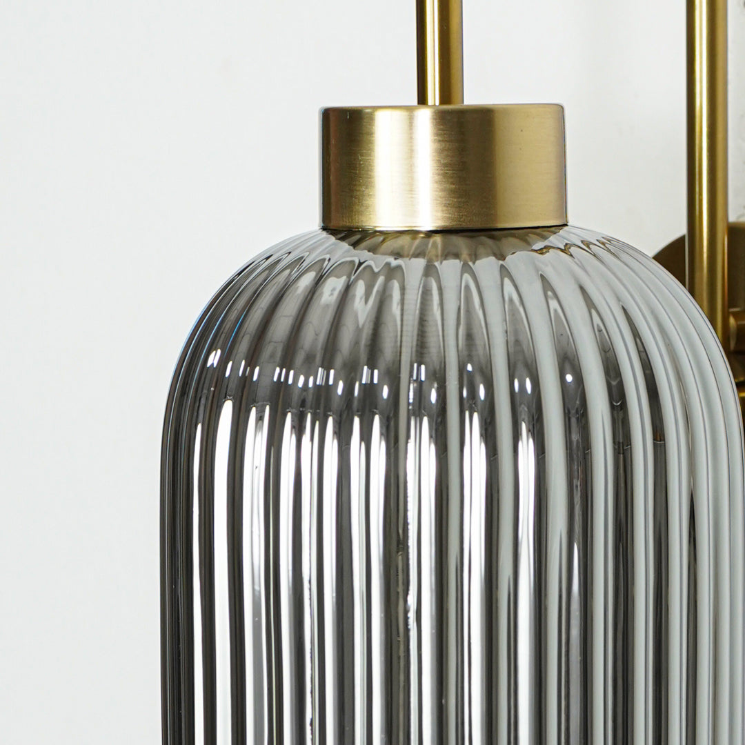 Closeup of gold metal wall light with ribbed glass shade showcasing detailed texture and premium finish for modern decor styling.