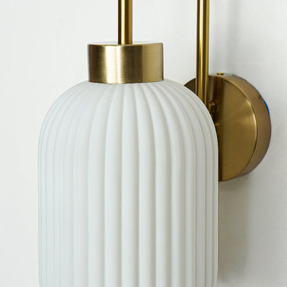 Closeup of gold metal wall light with white ribbed glass shade showcasing detailed texture and premium finish for modern decor styling.