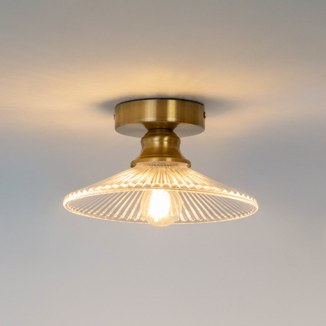 Modern gold metal ceiling light with ribbed glass shade and warm glow for elegant hallway decor spaces.