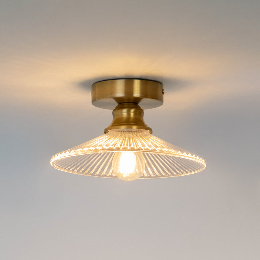 Modern gold metal ceiling light with ribbed glass shade and warm glow for elegant hallway decor spaces.