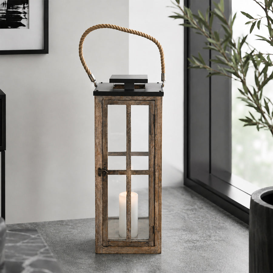 Wooden lantern with a candle inside on a stone floor near a window.