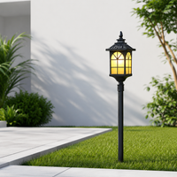 Classic black iron hexagonal cage glass lamp post lantern light on green grass lawn yard for rustic outdoor pathway styling.