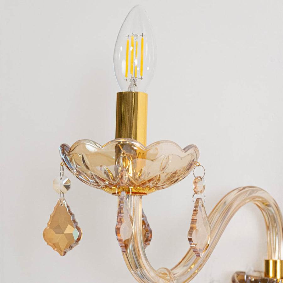 Closeup of golden wall light with crystal drops stylish candle style decorative wall mounted lighting fixture.