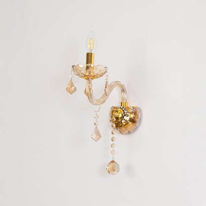 Golden wall light with crystal drops elegant candle style decorative fixture displayed on off white background.