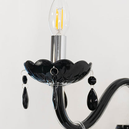 Closeup of black wall light with crystal drops stylish candle style wall mounted decorative lighting fixture.