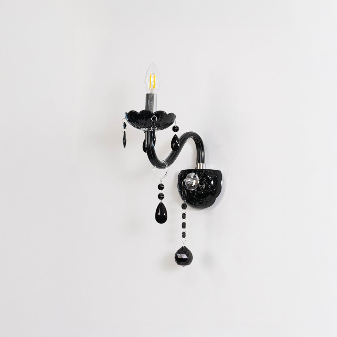 Black wall light with crystal drops elegant candle style wall mounted lighting shown on off white background.