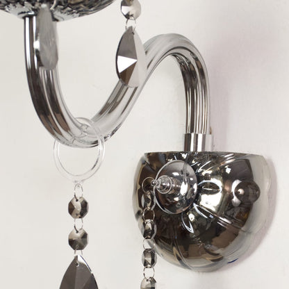 Closeup of chrome wall light showing curved metal arm and dark crystal drops for stylish modern interior lighting.
