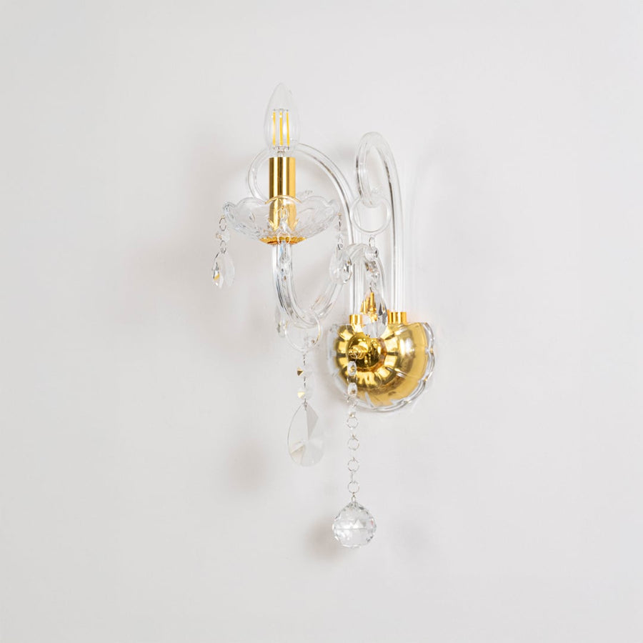 Crystal wall light with golden base and drops elegant wall mounted table lamping on off white background.