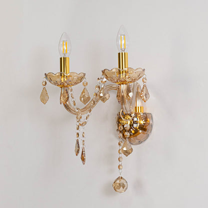 Golden wall light with crystal drops classic dual candle style fixture displayed on off white background.
