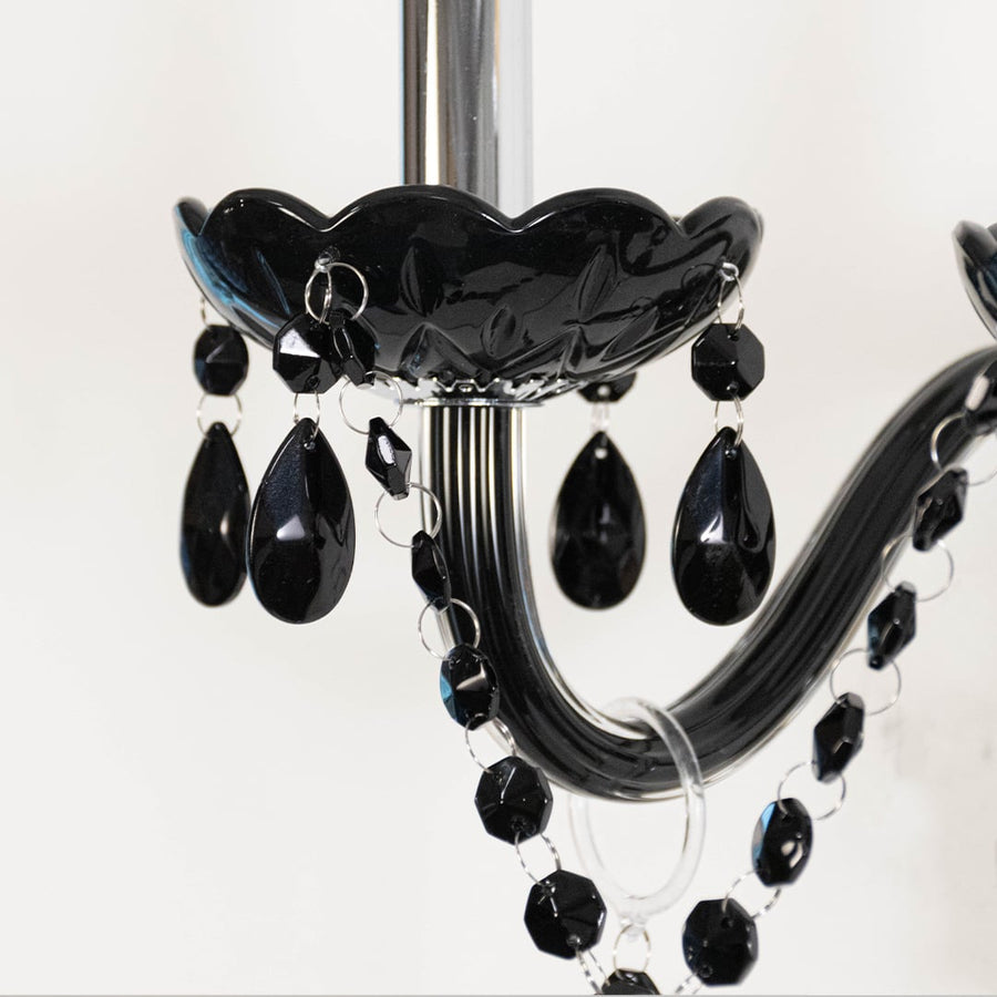 Closeup of black wall light with crystal drops dual candle style elegant decorative wall mounted lighting.