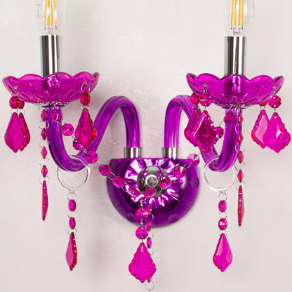 Closeup of pink wall light showing curved acrylic arms and bold crystal drops for eye catching modern interior lighting.