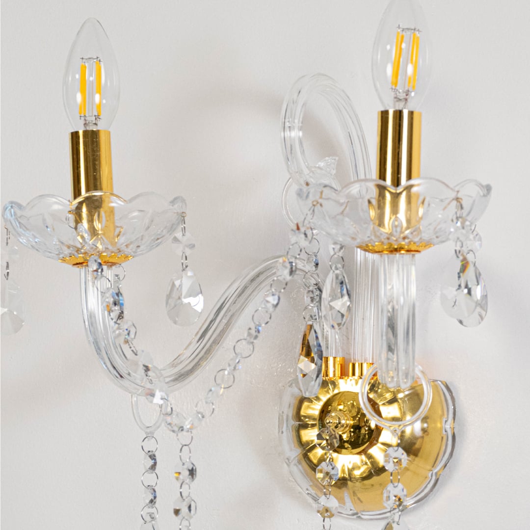 Closeup of elegant wall light with crystal elements gold metal finish candle style bulb holder and classic decor appeal.