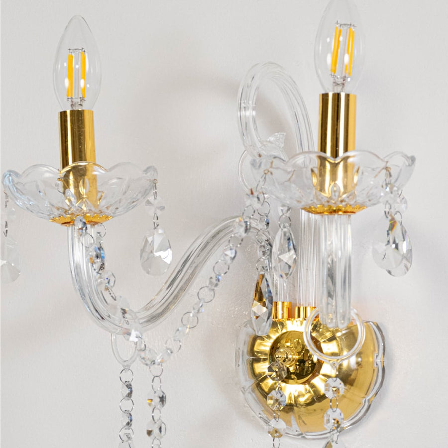 Closeup of elegant wall light with crystal elements gold metal finish candle style bulb holder and classic decor appeal.