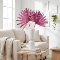 Minimal white vase with pink fan shaped leaves placed on coffee table adding artistic focal point to bright cozy living room Decor.