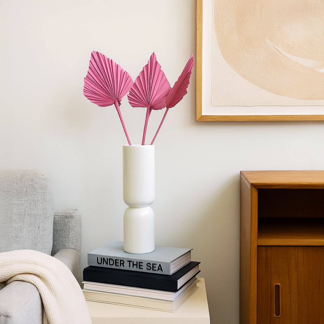 White ceramic vase with pink leaf stems styled on side table beside sofa creating soft modern living room Decor ambience.