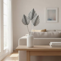 White ceramic vase with grey decorative leaves styled on table near sofa bringing calm neutral tones to modern home Decor.