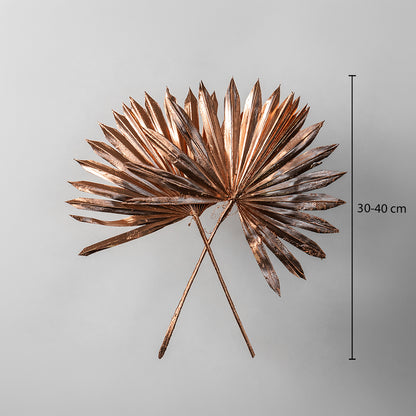 Two rose gold metallic painted dried palm sun fan leaves showing a thirty to forty centimeter height on white backdrop.