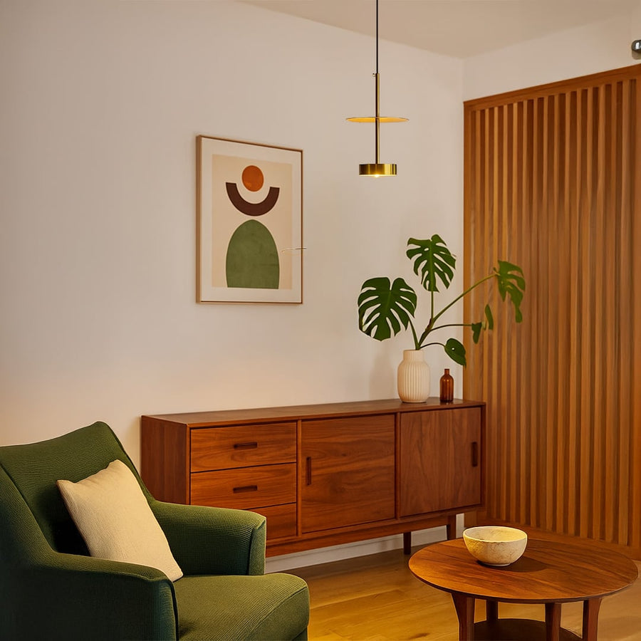 Gold metal pendant light above seating area creating sophisticated warmth and modern appeal.