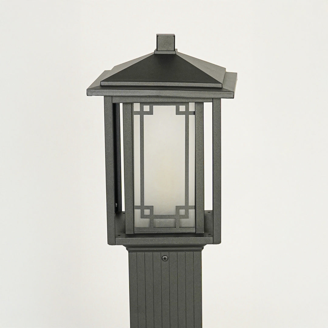 Close view of outdoor pole light with black metal body and glass enclosure showcasing durable weather resistant lighting design.
