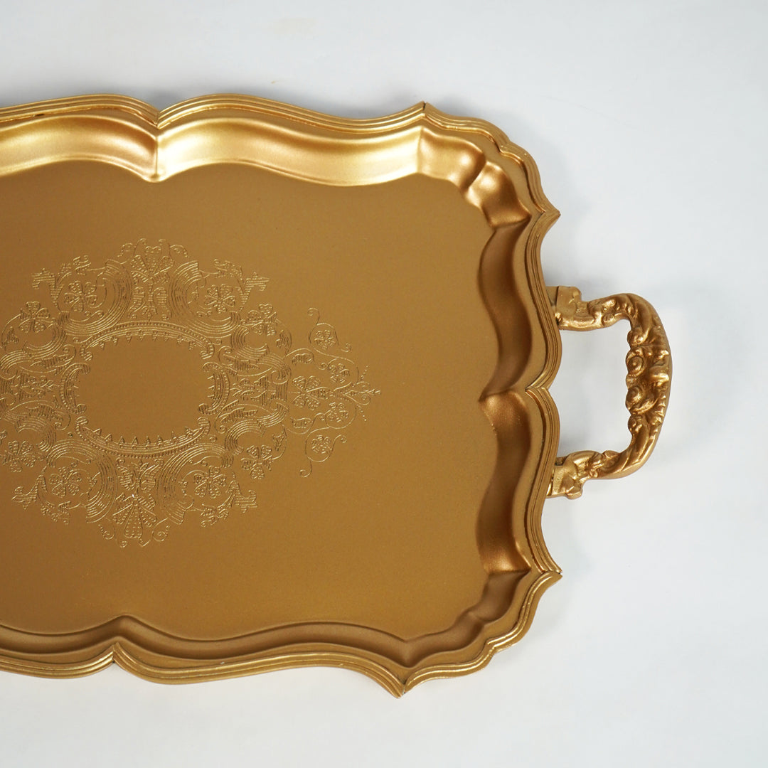 Closeup of luxury gold metal serving tray with embossed detailing for dining table and home decor styling.