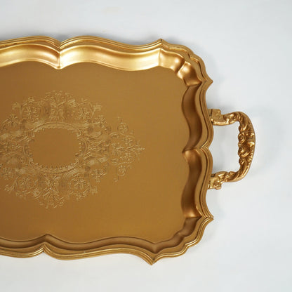 Closeup of luxury gold metal serving tray with embossed detailing for dining table and home decor styling.