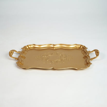 Elegant gold metal serving tray with ornate handles for dining table and home decor on white background image.