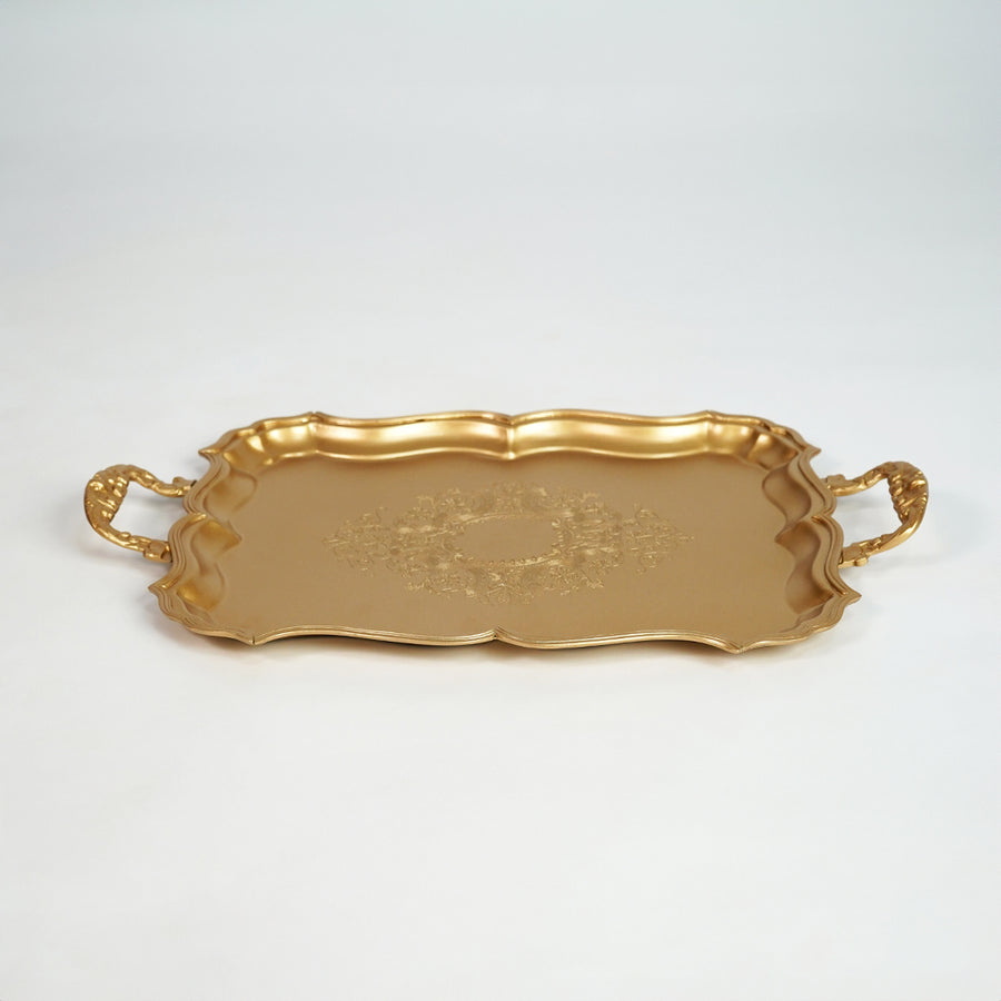 Elegant gold metal serving tray with ornate handles for dining table and home decor on white background image.