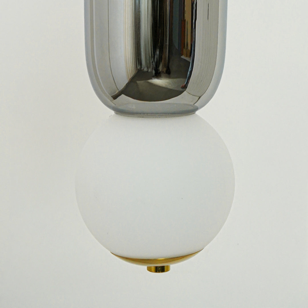 Closeup of chrome metal and white glass pendant light highlighting reflective finish and craftsmanship.