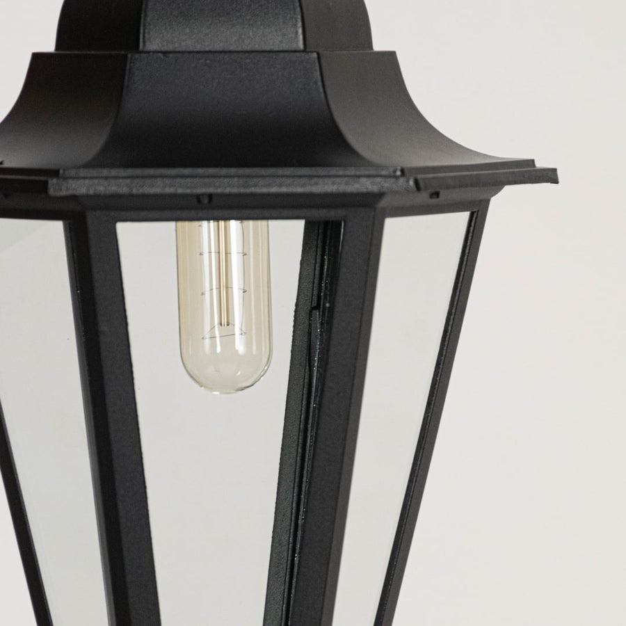 Classic black hanging lantern glowing on white background highlighting detailed frame and glass clarity.