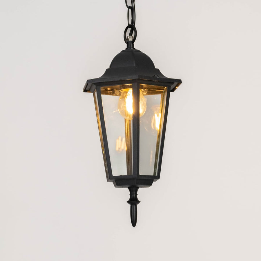 Modern black metal hanging lantern light with warm glow for elegant balcony and porch decor.