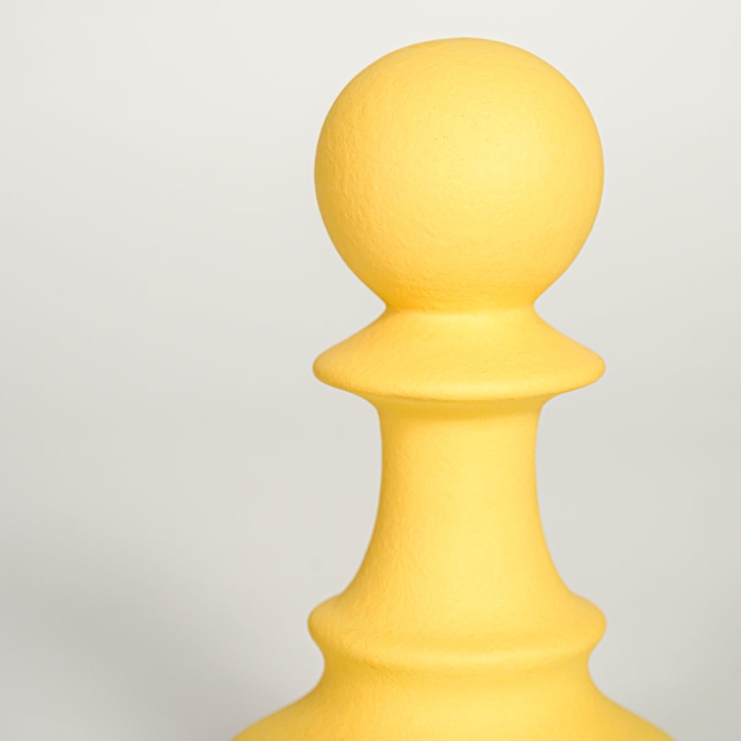 Closeup of Minimal yellow ceramic decorative chess pawn sculpture with soft matte surface ideal for home office shelf console or table decor.