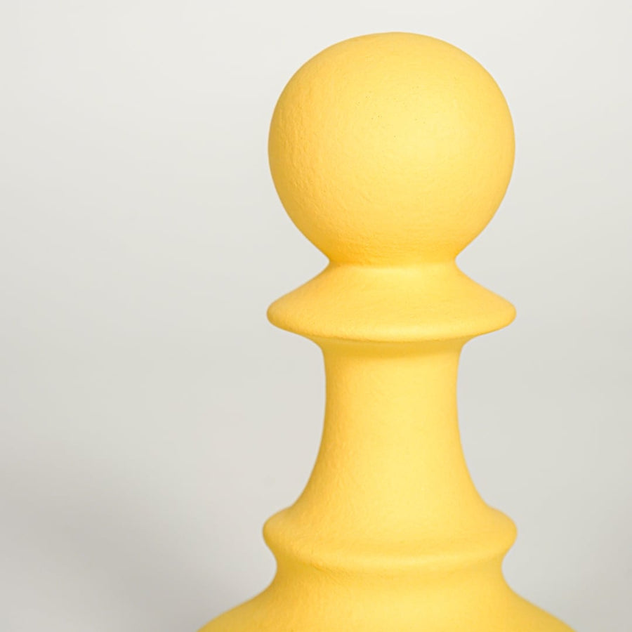 Closeup of Minimal yellow ceramic decorative chess pawn sculpture with soft matte surface ideal for home office shelf console or table decor.