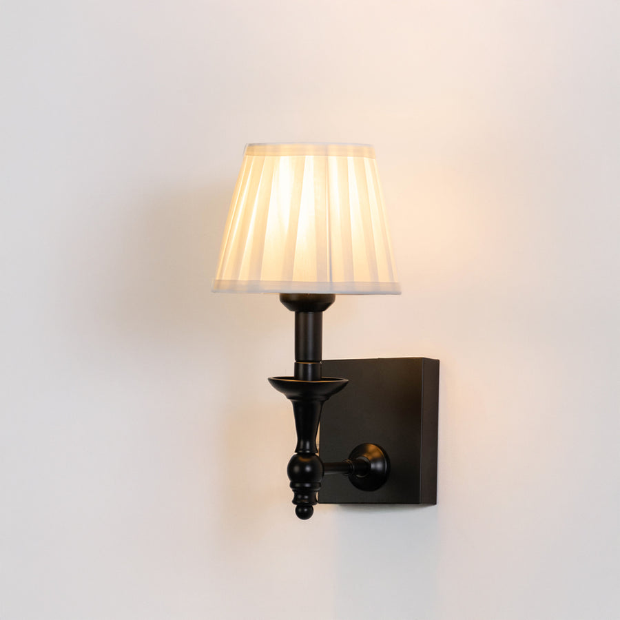Classic wall light in black metal finish with fabric shade for bedroom or living room ambient lighting decor white background.