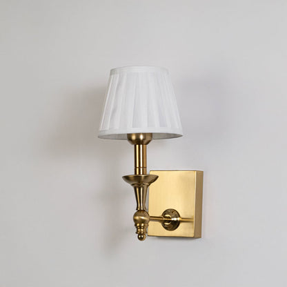 Gold wall sconce with white pleated lampshade shown on a plain white background for accurate product clarity.