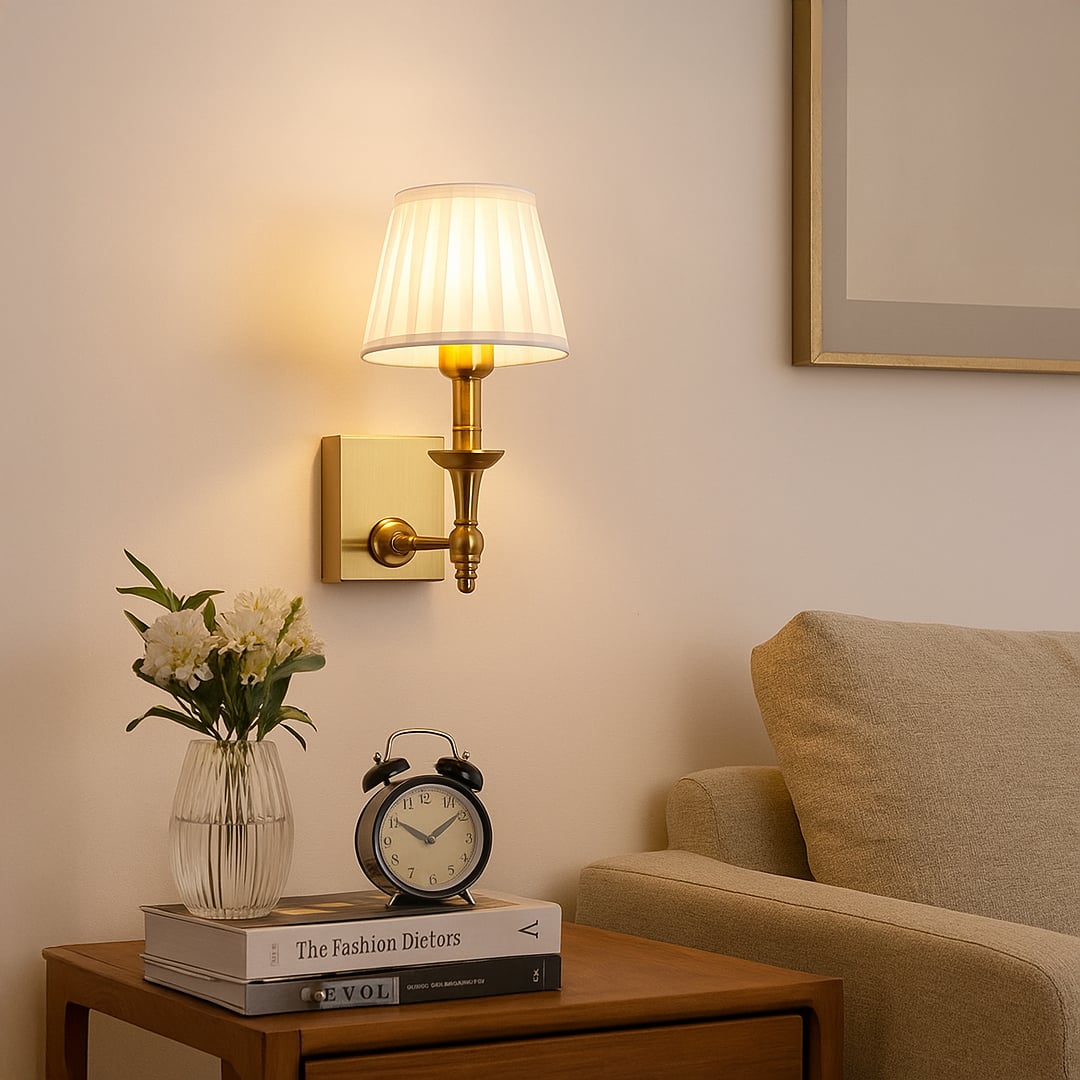 Gold metal wall sconce with white pleated shade adding warm ambient lighting to a modern elegant home interior.