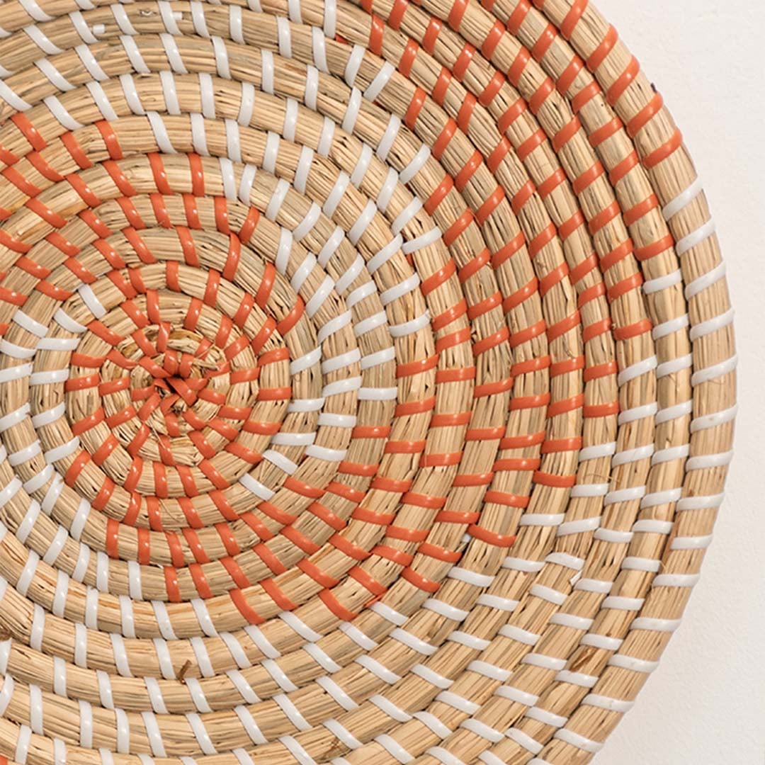Detailed closeup view of the tight weaving and painted orange sections on the natural seagrass wall basket surface quality.
