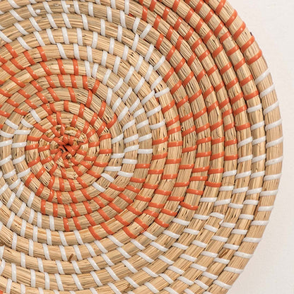 Detailed closeup view of the tight weaving and painted orange sections on the natural seagrass wall basket surface quality.
